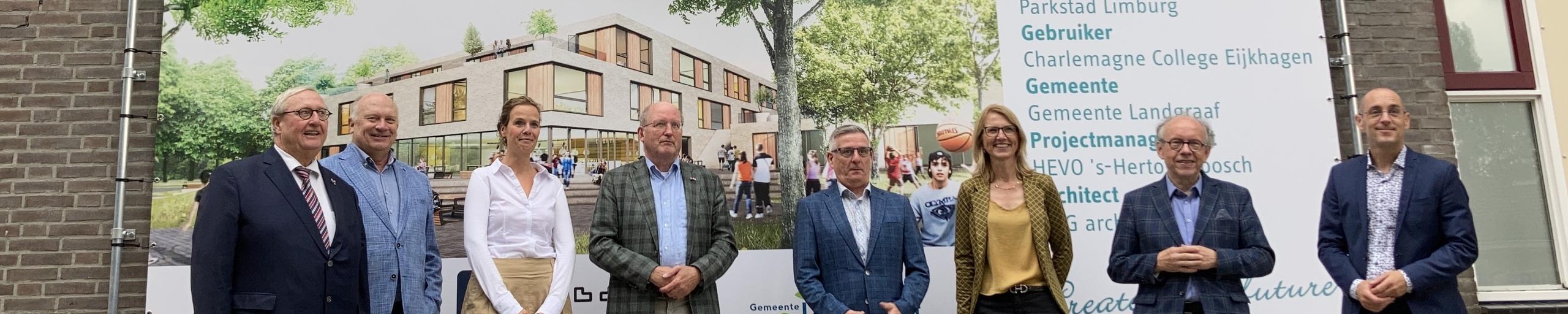 Een gedeelte van het college van de gemeente Landgraaf en directie van het Charlemagne college staan voor het bouwbord van het locatie Eijkahgen