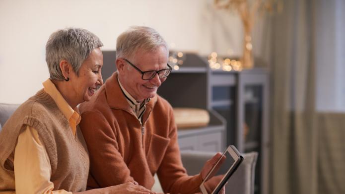 oudere man en vrouw met tablet in huiskamer