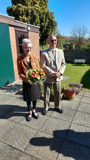 Helmy Vankan met Lintje en boeket bloemen naast haar echtgenoot