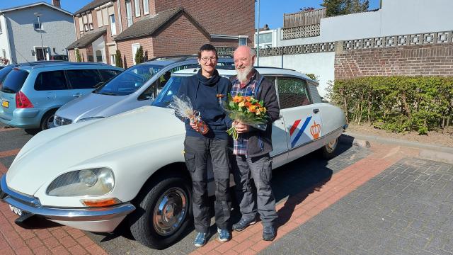 Mevrouw Quaedvlieg-de Jong met Lintje en haar echtgenoot met een boeket bloemen