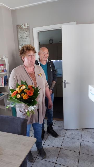 Mevrouw Petra Mommertz-Zwolen met Lintje en boeket bloemen en haar echtgenoot